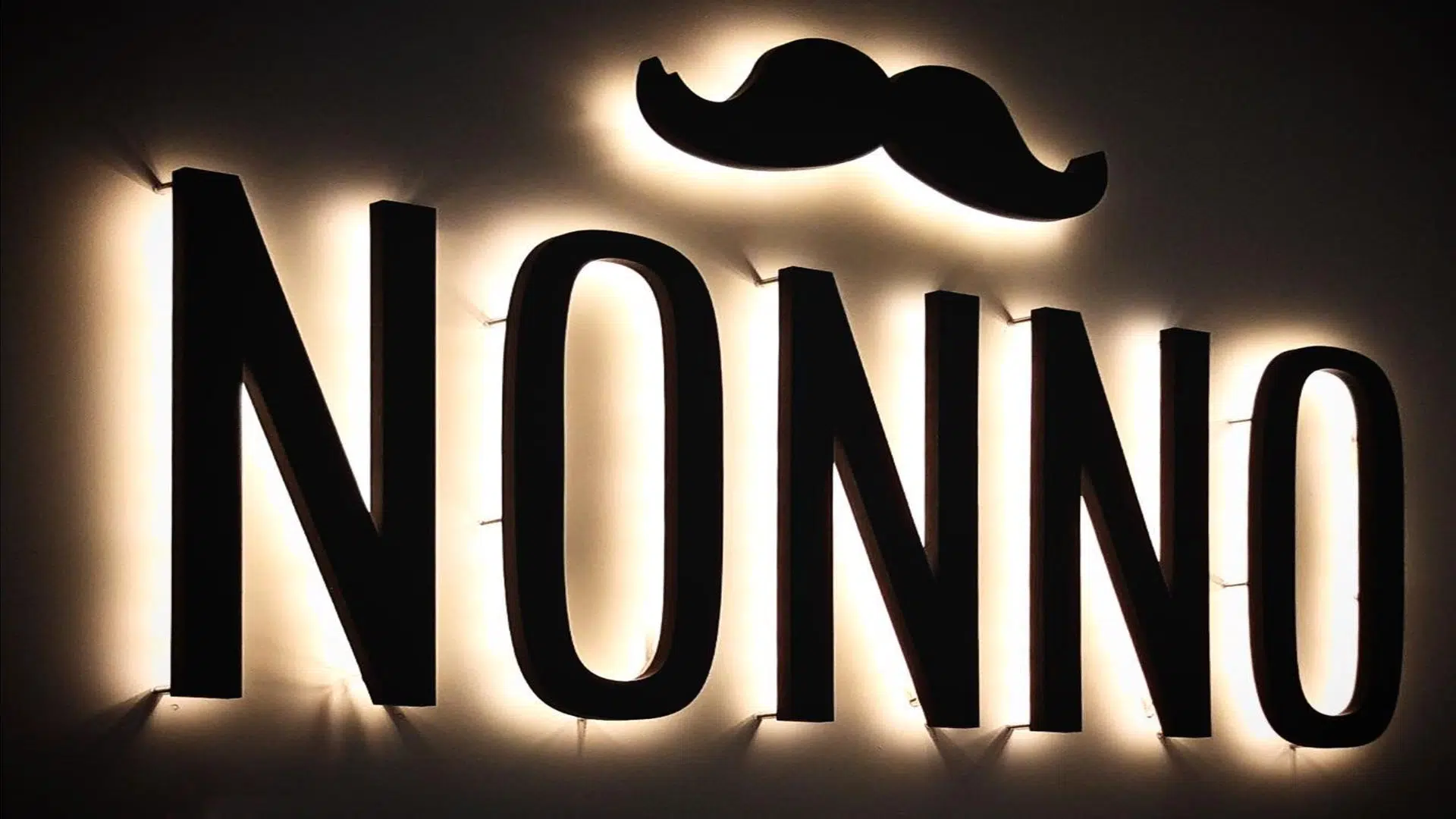 Indirect verlichte doosletters geplaatst met afstandshouders tegen de muur in een restaurant