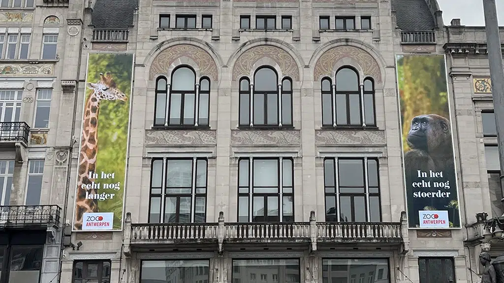 Outdoor banner spandoek met print op frontlit doek met rekkers gemonteerd in een buizenframe tegen de gevel van de zoo Antwerpen