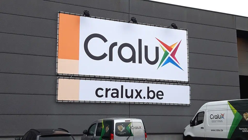 Outdoor banner spandoek met verlichting en print op frontlit doek met rekkers gemonteerd in een buizenframe tegen de gevel van een magazijn