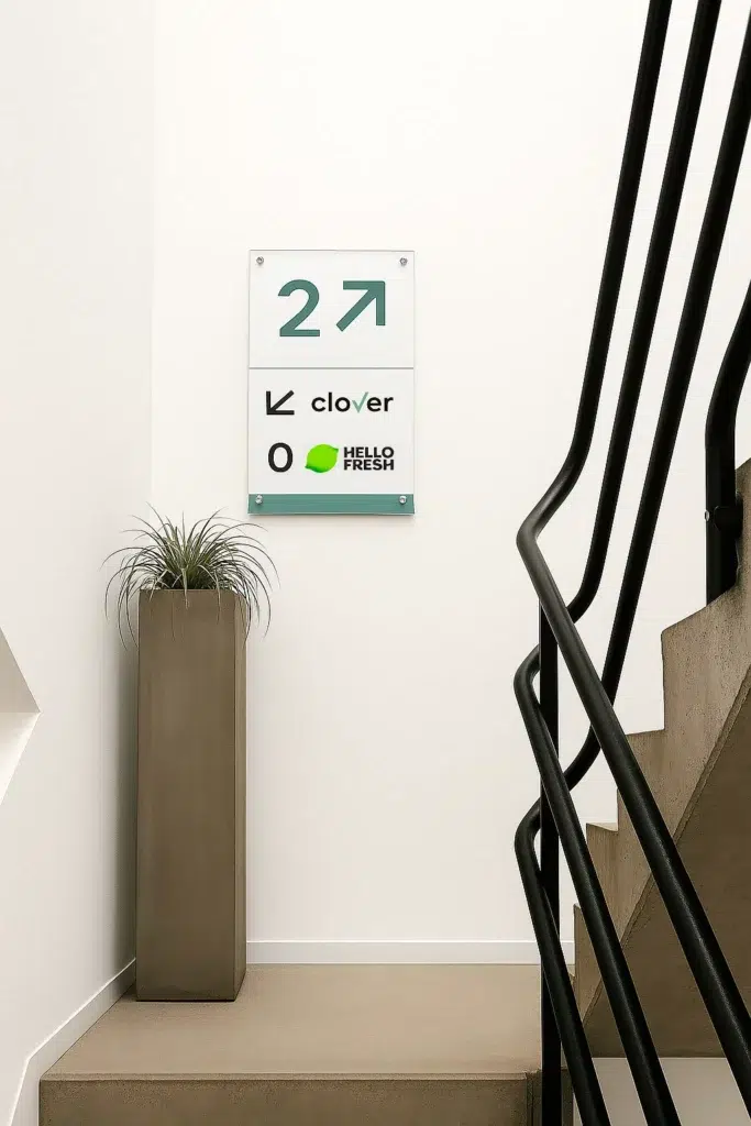 Helder Plexipaneel met belettering kleefletters en gemonteerd met afstandshouders op de muur AMS Antwerpen